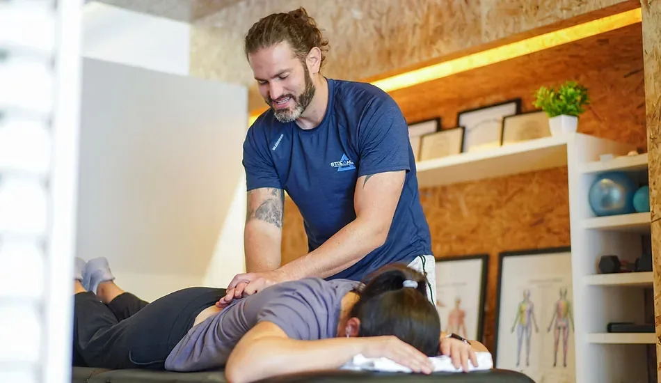 A clinician applying a two-hand low back technique to a patient lying prone at Streamline Performance Physical Therapy in Phoenix, AZ