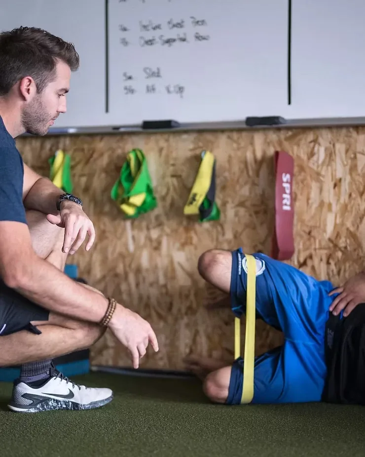 A coach watching a client perform a banded quadruped exercise at Streamline Performance Physical Therapy in Phoenix, AZ